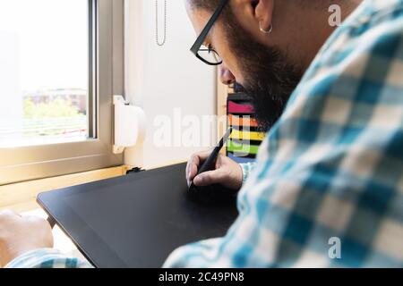 primo piano di un giovane uomo che si disegna con un tablet grafico, concetto di lavoro da casa Foto Stock