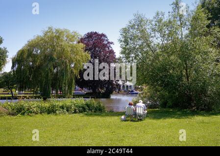 Una coppia anziana si rilassa mentre si siede sul fiume in una calda giornata estiva a Shepperton Surrey UK Foto Stock