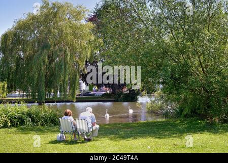 Una coppia anziana si rilassa mentre si siede sul fiume in una calda giornata estiva a Shepperton Surrey UK Foto Stock