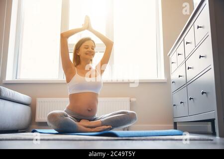 Donna entusiasta che ama lo yoga a casa durante la gravidanza Foto Stock