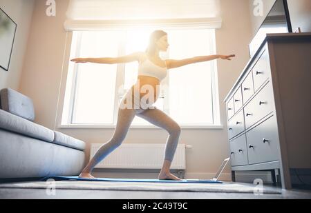 Donna che pratica yoga asana a casa durante la gravidanza Foto Stock
