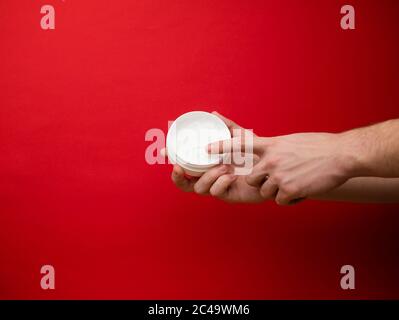 Mano maschio che tiene il tubetto di plastica senza marchio con crema bianca. Flacon per crema, toilette. Bottiglia per prodotti cosmetici professionali. Cura della pelle e bellezza Foto Stock