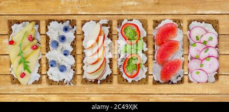 Sandwich con crema di formaggio e frutti di bosco freschi e frutta e verdura. Fresco e salutare antipasto spuntino con pane croccante detto "Knäckebrot". Foto Stock