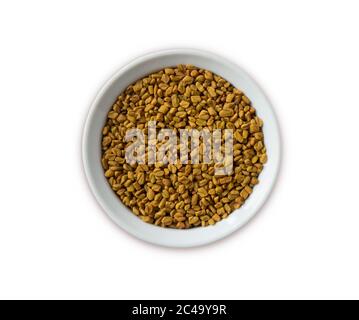 Semi di fenugreek in una ciotola di legno isolata su bianco. Semi di fenugreek isolati su sfondo bianco. Vista dall'alto. Fenugreek con spazio di copia per il testo. Foto Stock