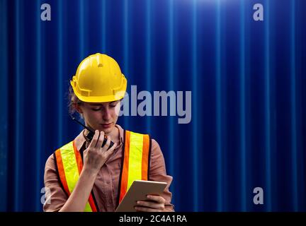 La caposquadra femminile utilizza walkie talkie e tablet per computer per controllare il lavoro nel settore industriale Foto Stock