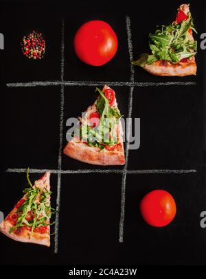 TIC-tac-TOE gioco tra pizza e ingredienti su sfondo nero. Contestuale Foto Stock