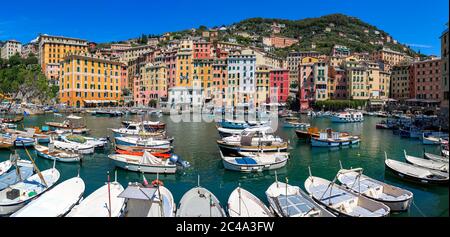 Panorama di piccolo porto con barche e case colorate tipiche sullo sfondo sotto il cielo blu nella città di Camogli in Liguria, Italia. Foto Stock