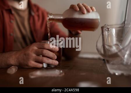 Primo piano di uomo seduto al tavolo e versando il vino dalla bottiglia nel suo bicchiere ha problemi con l'alcol Foto Stock