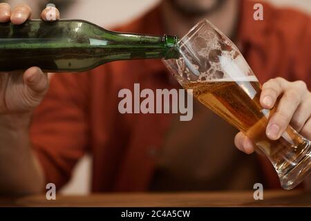 Primo piano di un uomo maturo che versa la birra dalla bottiglia nel bicchiere Foto Stock