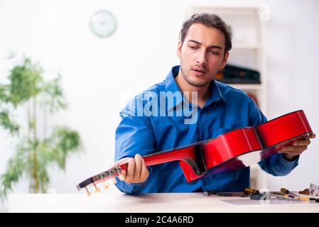 Giovane uomo riparatore riparando la chitarra Foto Stock