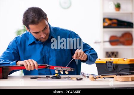 Giovane uomo riparatore riparando la chitarra Foto Stock