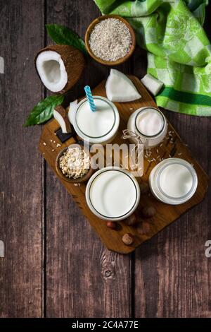 Concetto di cibo vegano sano. Assortimento di latte vegano non caseario biologico di cocco, noci, farinata d'avena, riso su un tavolo da cucina. Vista dall'alto, sfondo piatto Foto Stock