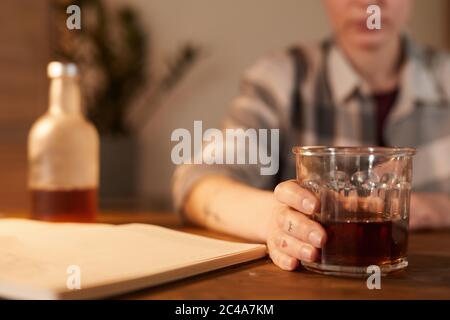 Primo piano di giovane donna seduta al tavolo e bevendo cocktail alcolici a casa Foto Stock