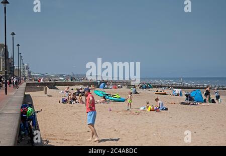 Portobello, Edimburgo, Scozia, Regno Unito. 25 giugno 2020. 2° giorno di tempo molto caldo anche se più fresco per iniziare con una brezza fresca come ha cominciato a riscaldare vapore ha cominciato a salire dalla sabbia bagnata causando una foschia, temperatura ha raggiunto 20 gradi all'ora di pranzo, più persone fuori prima di là erano ieri, Luppolyusing schermo solare per proteggerli dai raggi UV più alti che gli agenti atmosferici stanno avvertendo circa. Foto Stock