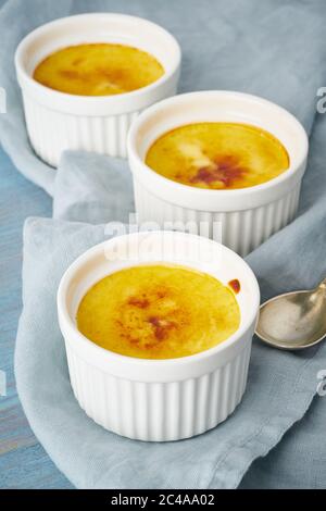 Crema catalana, dessert spagnolo in tre ramekin su tavolo blu, verticale Foto Stock