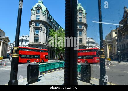 Londra, Regno Unito. 25 giugno 2020. Regno Unito Meteo: Un autobus rosso a due piani riflesso in una vetrina al sole vicino allo Strand, su ciò che si prevede sia il giorno più caldo dell'anno finora. L'indice UV dell'Ufficio MET dovrebbe raggiungere livelli eccezionalmente elevati, a causa di cielo limpido e dell'assenza di percorsi per il vapore degli aeromobili a causa di una riduzione dei voli durante la pandemia del coronavirus. Credit: Stephen Chung / Alamy Live News Foto Stock