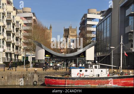 La Cattedrale Anglicana di Bristol è incorniciata dai moderni uffici e alloggi del vicino porto con una vecchia barca di legno ormeggiata al qua Foto Stock