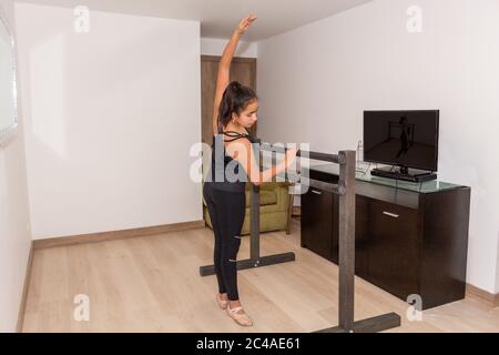 La bambina pratica balletto, danza, ginnastica su un bar all'interno della sua casa Foto Stock