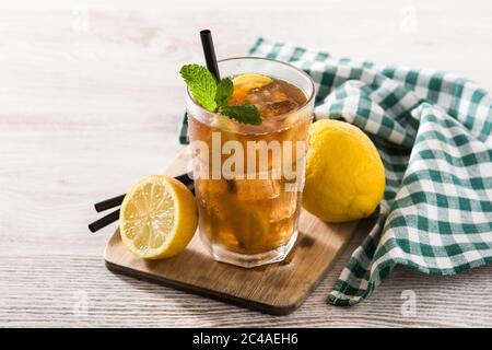 Bevanda a base di tè freddo con limone in vetro e ghiaccio su tavolo di legno bianco Foto Stock
