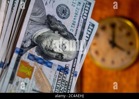 Primo piano di molte banconote in dollari USA con orologio vintage in background. Il tempo è concetto di denaro Foto Stock