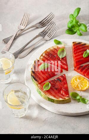 fette di anguria grigliate con limone e basilico. dessert estivo Foto Stock