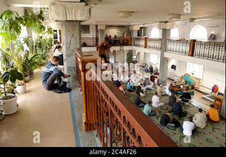 Seguaci di Krishna seduti su un pavimento e ascoltando la predicazione dei guru in un tempio Foto Stock