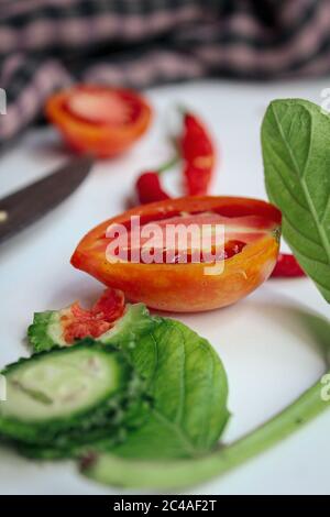 Peperoncino rosso e pomodoro affettati su una superficie bianca Foto Stock