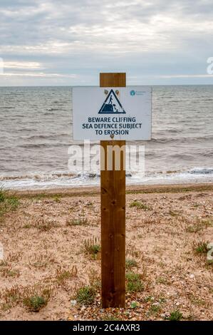 Un cartello sulla spiaggia di Snettisham avverte della formazione di scogliere a causa di un erosione delle difese marine. Foto Stock