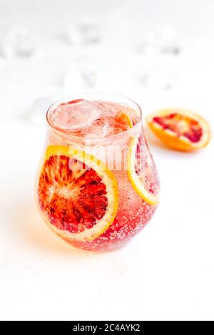 Un cocktail ghiacciato frizzante con arancio sangue su sfondo bianco Foto Stock