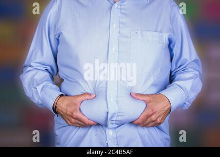 uomo con un pancia grande che indossa una camicia, tenendo la sua wheatwamp, dieta Foto Stock
