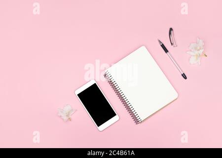 Sfondo minimalista. Notebook, penna, telefono cellulare su sfondo rosa. Ricerca di lavoro o apprendimento a distanza. Foto Stock