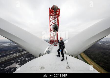 Assemblaggio di una centrale eolica, un assemblatore per centrali eoliche sta lavorando ad un'altezza di 100 metri durante l'assemblaggio dell'anello del rotore con Foto Stock