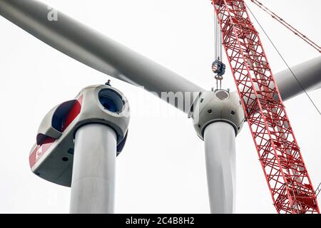 Assemblaggio di una centrale eolica, un assemblatore per centrali eoliche sta lavorando ad un'altezza di 100 metri durante l'assemblaggio dell'anello del rotore con marciume Foto Stock