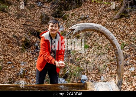 ragazzo di 13 anni che ottiene acqua fresca in alta savoia, francia Foto Stock