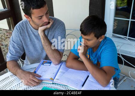 Giovane uomo che aiuta il fratello minore con i compiti Foto Stock