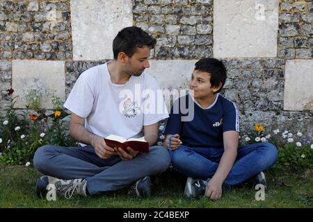 Fratelli che leggono la bibbia fuori da un chuch in Normandia, Francia. Foto Stock