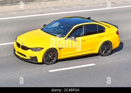 Vista laterale e anteriore del tetto dell'antenna della quattro porte gialla Auto Bmw top nera e conducente che guida lungo Targhe commerciali sul cruscotto strada autostradale per il Regno Unito Foto Stock