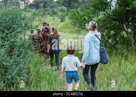 Un ragazzo e sua madre, turisti su un sentiero a piedi seguendo i membri del popolo San, boscimani. Foto Stock