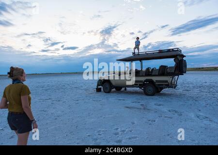 Ragazzo di 6 anni e sorella maggiore in piedi sulla cima del veicolo safari, Nxai Pan, Botswana Foto Stock