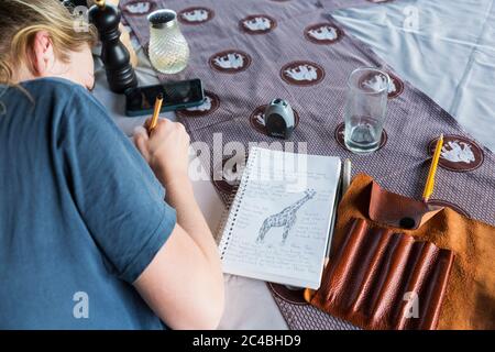 Una ragazza di tredici anni che scrive nel suo giornale, campo di tenda, Botswana Foto Stock