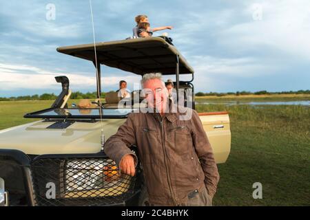 Una guida sorridente e una famiglia di turisti in un veicolo safari. Foto Stock