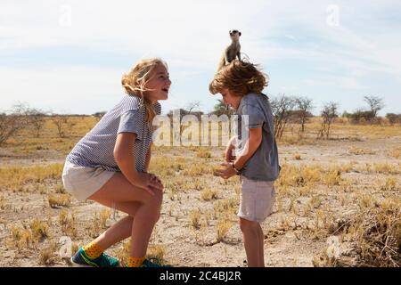 Ragazzo di 5 anni con Meerkat in testa, deserto di Kalahari, Saline di Makgadikgadi, Botswana Foto Stock