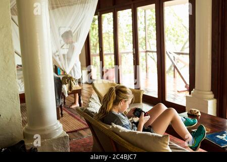 Ragazza di 12 anni che guarda lo smartphone in una camera d'albergo, Botswana Foto Stock