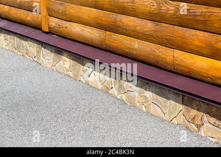 casa di tronchi con un fondamento di pietra su una strada asfaltata, un primo piano dei dettagli della struttura. Foto Stock