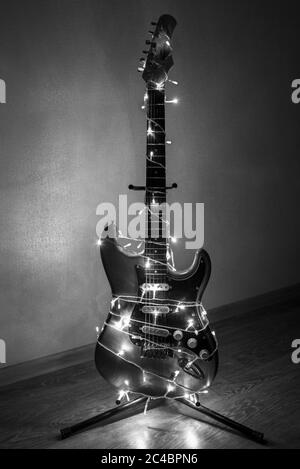Chitarra elettrica avvolta in coloratissimi colori brillanti, l'idea della musica di vacanza, foto in bianco e nero Foto Stock
