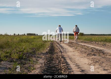 Padre e figlio a cavallo con biciclette all'aperto. Foto Stock