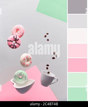 Tavolozza di colori che si abbina a un'elegante levitazione astratta di ciambelle rosa e verde menta e tazza di caffè espresso con chicchi di caffè volanti. Concetto alla moda Foto Stock