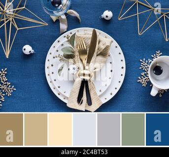 Tavolozza di colori corrispondenti da elegante tavolo di Natale su classico panno di lino blu con cina bianca, utensili dorati e metallo esha geometrico Foto Stock