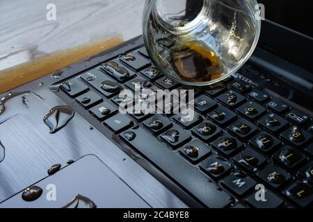 Il caffè viene versato accidentalmente sul computer portatile. La tastiera è piena di liquidi e il computer è rovinato. Foto Stock