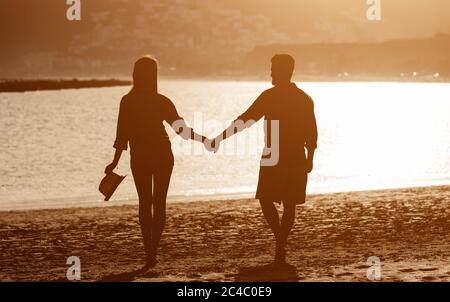 Giovane coppia che gode di una vacanza sulla spiaggia tropicale - romantica amanti silhouette divertirsi insieme in vacanza estiva Foto Stock